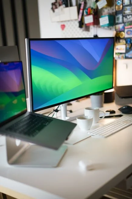 Due monitor su una scrivania, che mostrano design web in un ambiente d’ufficio moderno.